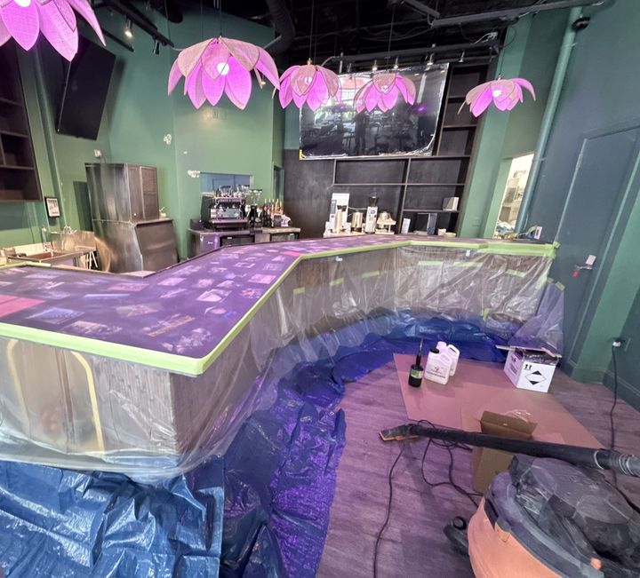 Bar top with sealed photos under purple accent lighting while it cures