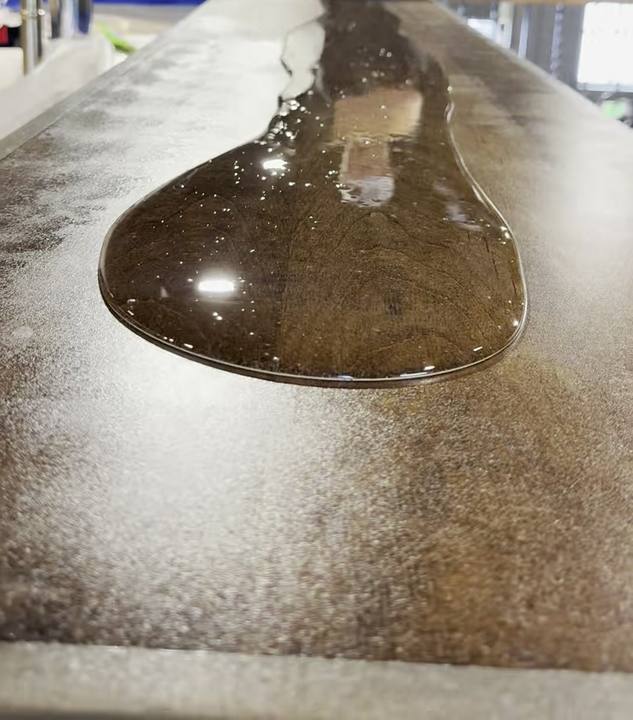 Pool of clear epoxy spreading across a wood bar top