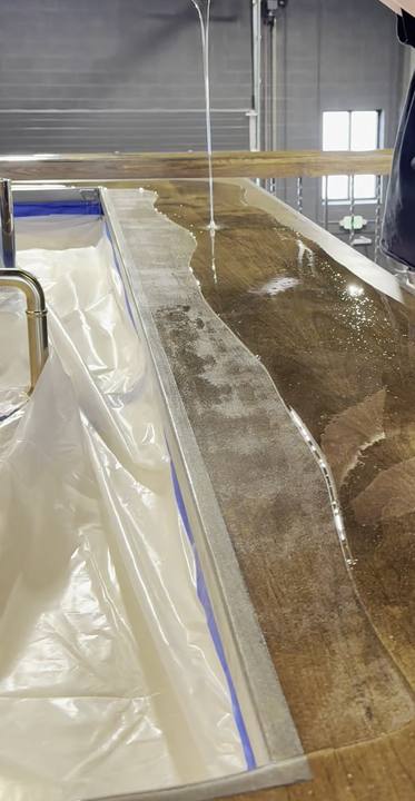 Clear epoxy poured in a thin stream onto a wood bar top