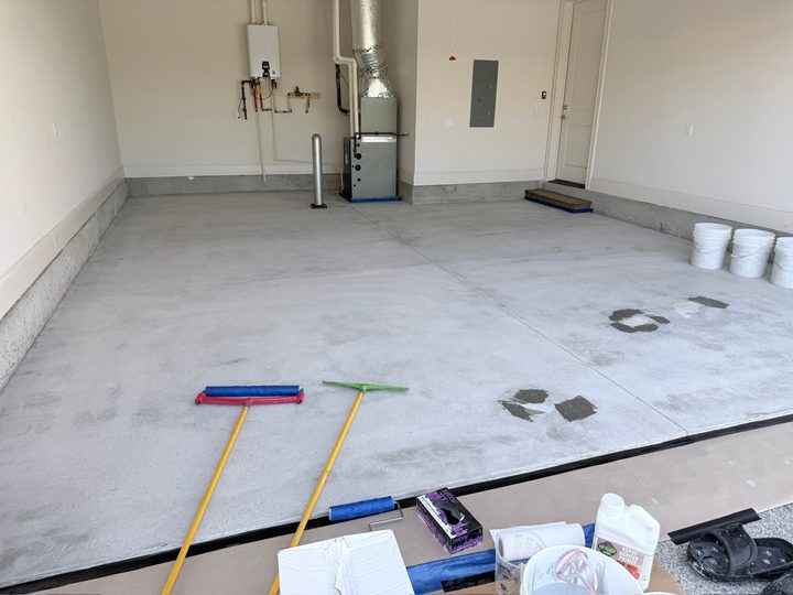 Garage slab after grinding, with patched spots and rollers ready before coating