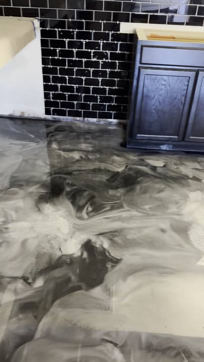 Silver metallic floor running up to dark cabinets and black subway tile